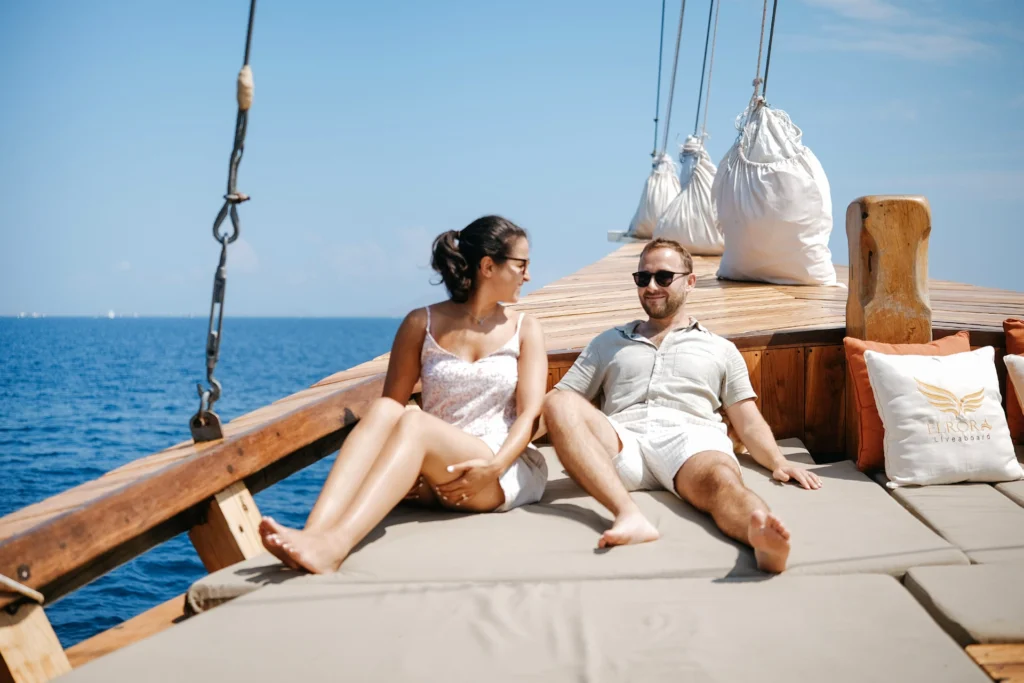 Couple relaxing on a luxury Phinisi deck during a one day trip in Labuan Bajo with ocean views in