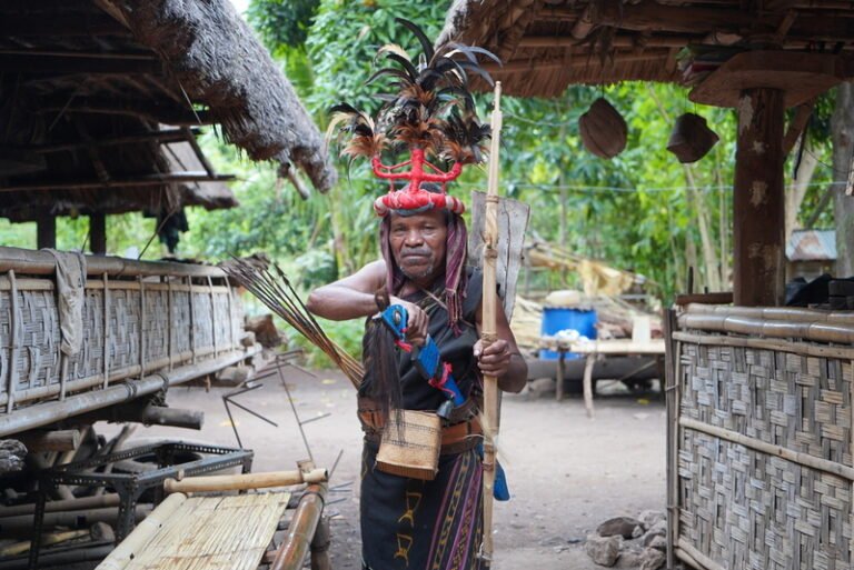 Pria dengan pakaian adat tradisional di desa budaya Pulau Flores sedang memegang tombak dan busur sebagai simbol budaya lokal