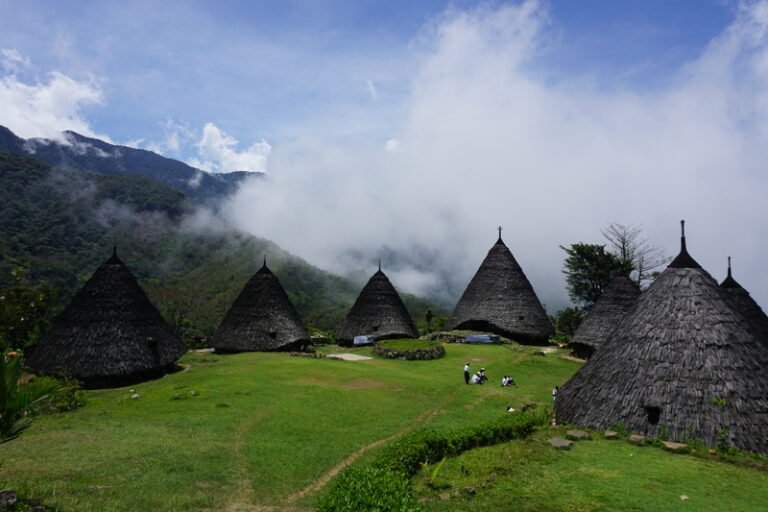 Traditional Mbaru Niang houses in Wae Rebo Village surrounded by mountains and mist, showcasing unique culture in East Nusa Tenggara