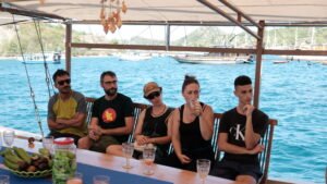 wisatawan menikmati perjalanan kapal phinisi di Labuan Bajo dengan pemandangan laut dan pulau eksotis