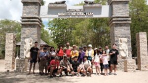 Sekelompok wisatawan berfoto bersama di gerbang masuk Taman Nasional Komodo dengan tulisan “Welcome to Komodo National Park” di Labuan Bajo.