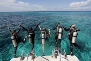 Group of scuba divers jumping into clear blue water in Labuan Bajo, preparing for a diving adventure in Komodo National Park.