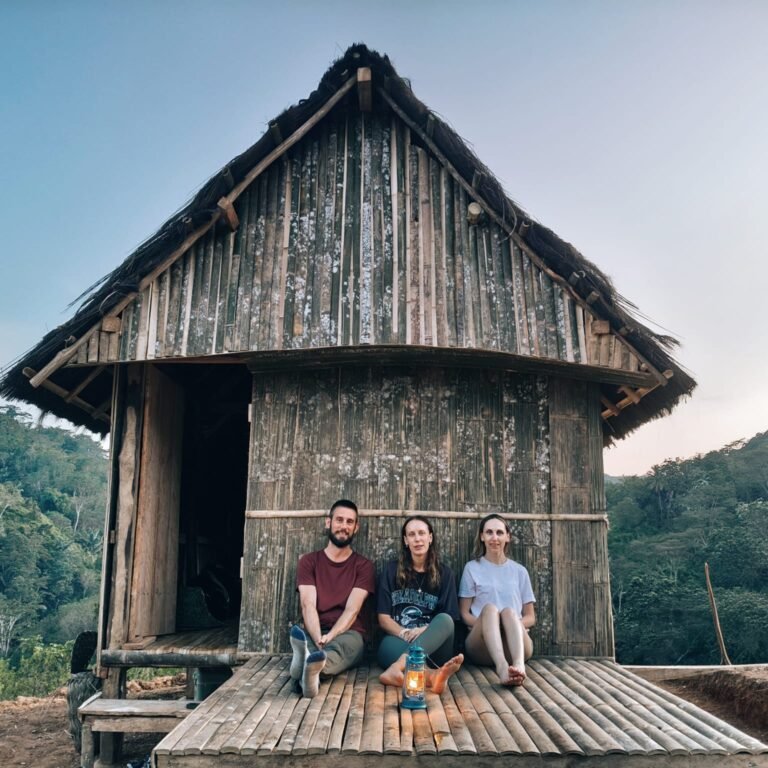 International travelers relaxing in front of a traditional bamboo house in Flores village, authentic cultural experience in Flores Indonesia by Visit Labuan Bajo Komodo