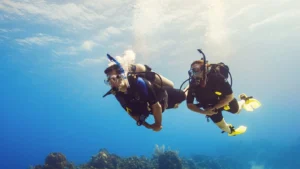 German couple scuba diving together in the clear blue waters of Komodo National Park during a romantic luxury dive trip in Labuan Bajo, Indonesia.