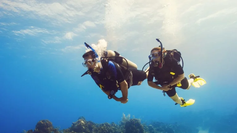 German couple scuba diving together in the clear blue waters of Komodo National Park during a romantic luxury dive trip in Labuan Bajo, Indonesia.