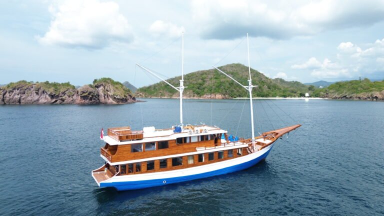 Arfisyana 02 Liveaboard kapal phinisi mewah berlayar di perairan Labuan Bajo dengan latar pulau tropis dan laut biru jernih-Visit Labuan Bajo