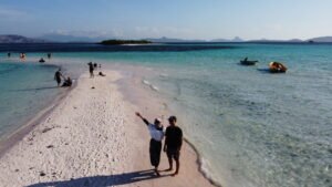 Couple enjoying a romantic tropical getaway on a white sandbar in Komodo National Park with crystal-clear turquoise water and beautiful island scenery — Visit Labuan Bajo Komodo.