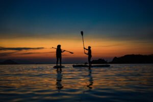 Sunset Labuan Bajo dengan aktivitas paddle board di laut tenang, wisata seru bersama visit labuan bajo”