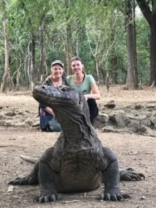Travelers posing with a Komodo dragon in Komodo National Park, Labuan Bajo, Flores Indonesia during an unforgettable wildlife and island adventure tour.