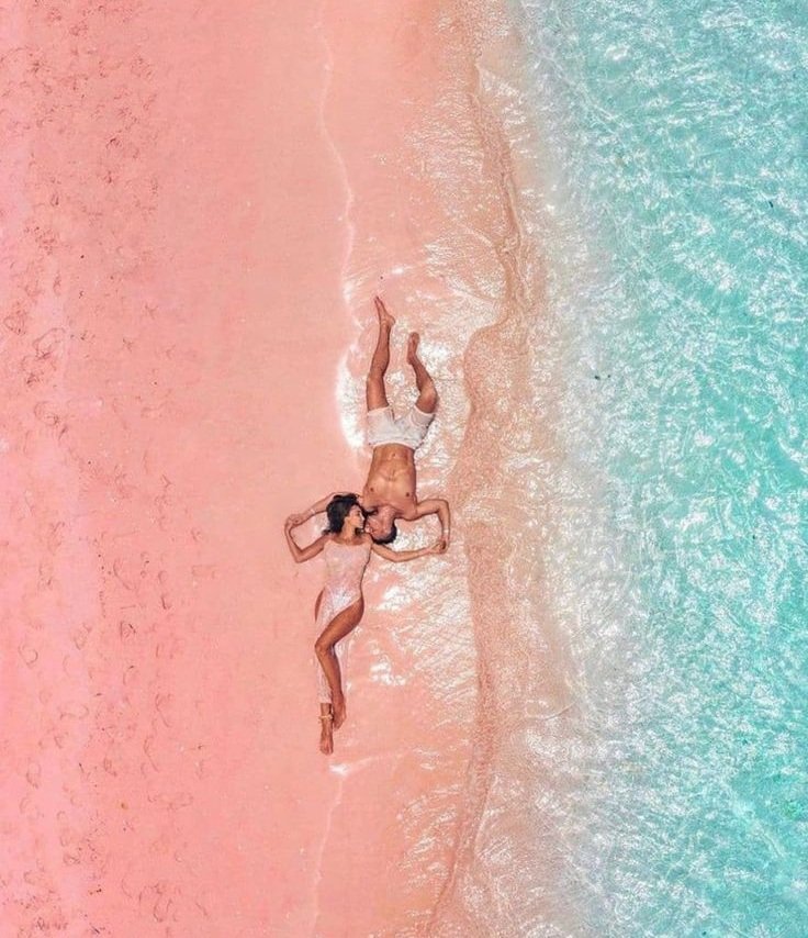 Couple relaxing on Pink Beach Komodo Island during a romantic Flores Island travel adventure in Labuan Bajo, Indonesia