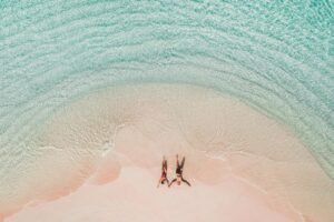 Beach couple relaxing on pink sand beach with crystal-clear turquoise water in Komodo National Park Indonesia