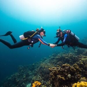 Couple enjoying a romantic scuba diving experience in Labuan Bajo surrounded by colorful coral reefs and clear blue waters in Komodo National Park.