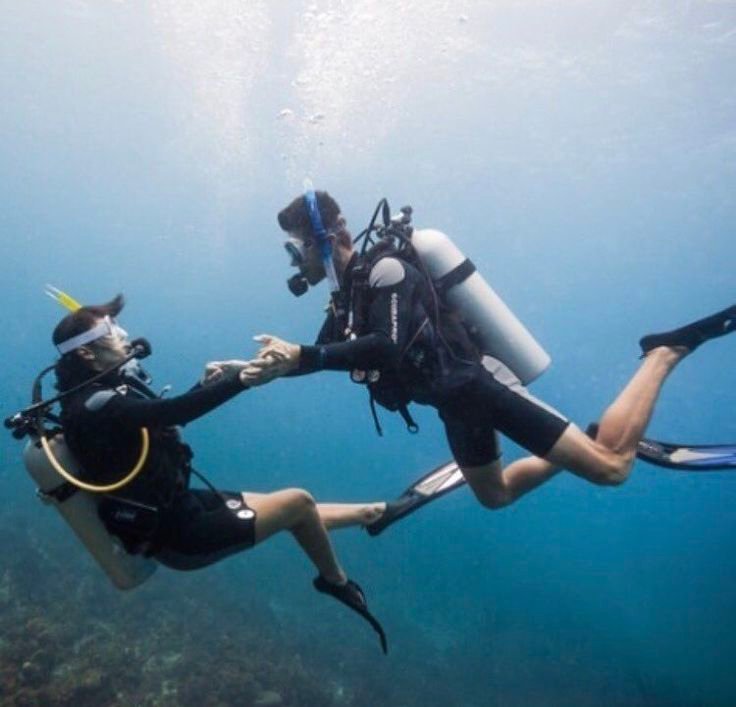 Couple scuba diving during PADI certification training in Komodo, Labuan Bajo, exploring clear blue waters and underwater adventure together. Fokus Keywords: