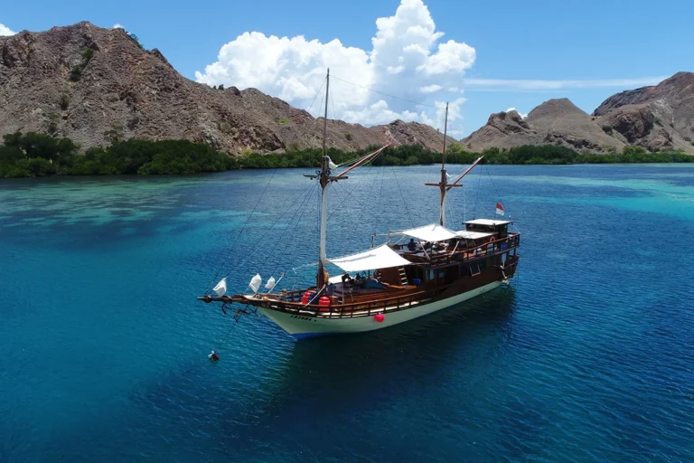 Luxury phinisi boat sailing in Komodo National Park with crystal clear water, tropical islands, private Komodo cruise, and premium island hopping experience in Labuan Bajo.