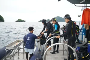 Scuba divers preparing for an underwater adventure aboard a dive boat in Komodo National Park, Indonesia, before entering the crystal-clear waters of Labuan Bajo.