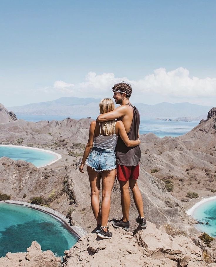 Couple enjoying the breathtaking panoramic view from Padar Island viewpoint in Komodo National Park, Labuan Bajo, Indonesia.