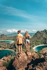 Travelers enjoying the stunning Padar Island viewpoint overlooking turquoise bays and dramatic hills in Komodo National Park, Indonesia.