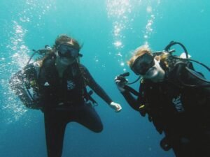 Two scuba divers participating in a dive course in Labuan Bajo, exploring the clear blue waters of Komodo National Park during underwater training.