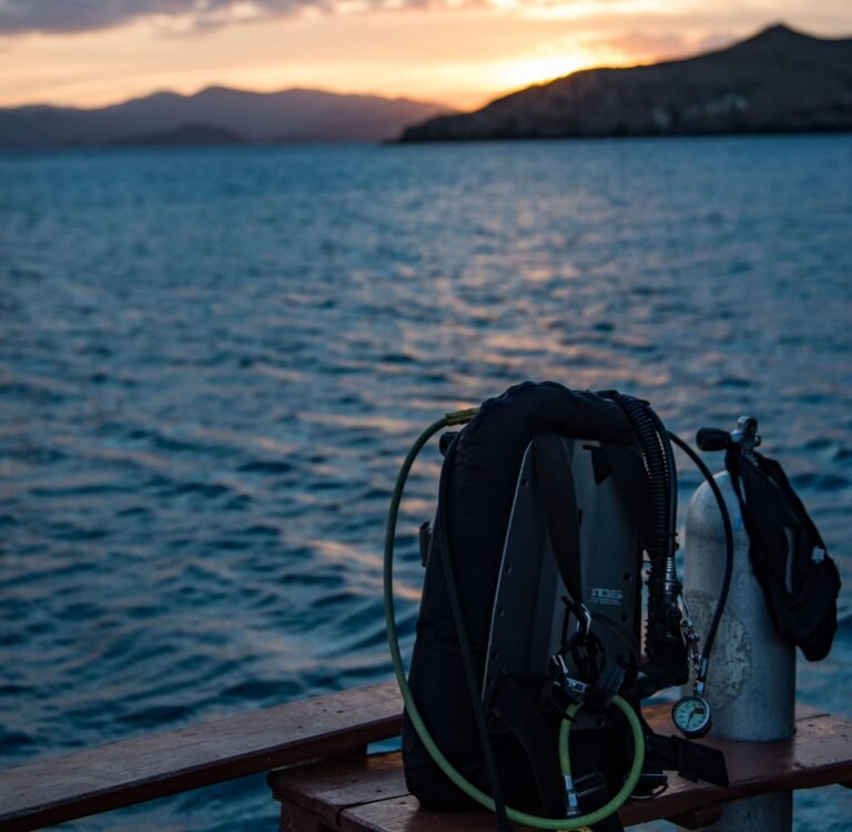 Scuba diving equipment prepared on a boat deck at sunset in Komodo National Park, Indonesia, before a real ocean dive certification experience.